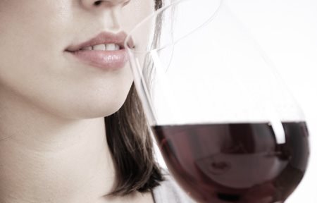 Mujer bebiendo un vaso de vino tinto.