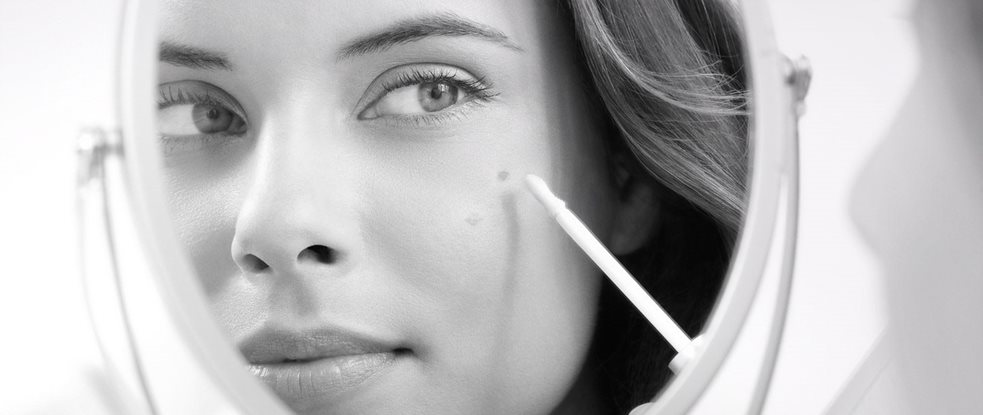 Mujer aplicándose Eucerin Even Brighter Corrector de Manchas mientras se contempla en el espejo
