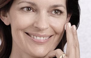 Mujer aplicándose crema en la cara.