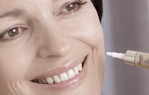 Mujer aplicándose un producto Eucerin sobre su mejilla izquierda.