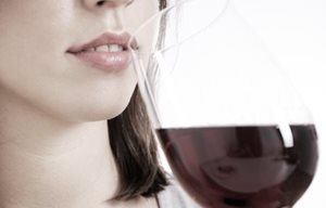 Mujer bebiendo un vaso de vino tinto.