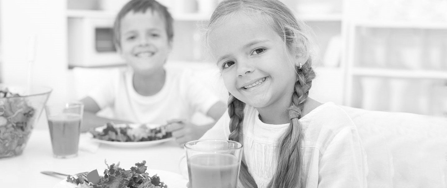 Un niño y una niña desayunando en la mesa de la cocina