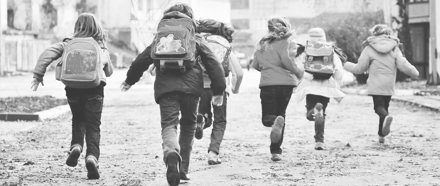 Un grupo de niños corriendo por la calle hacia el colegio
